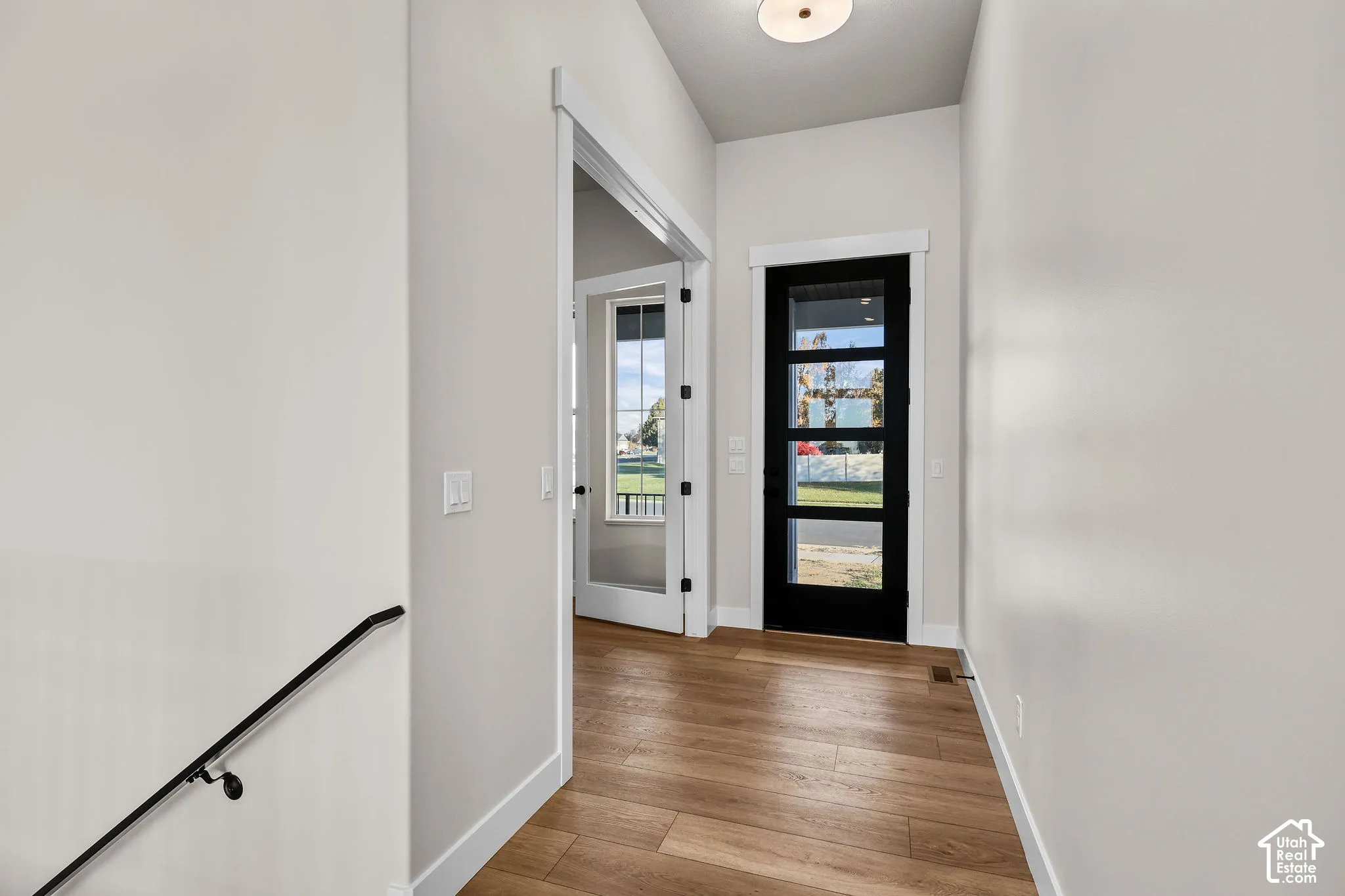 Foyer featuring wood-finish flooring, a modern black entry door with integrated glass panels, recessed ceiling light, and a white interior door