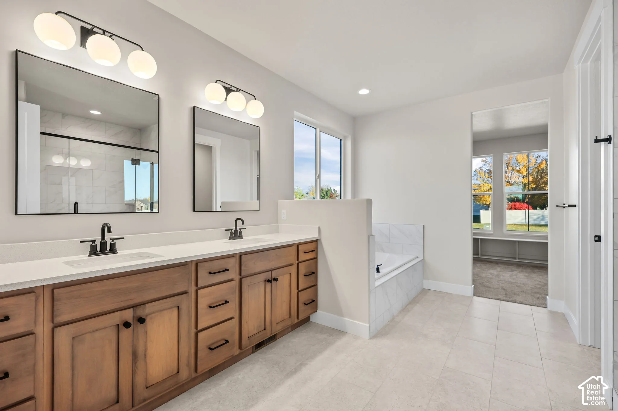 Dual vanity featuring wood cabinetry with black hardware, white countertops, and undermount sinks