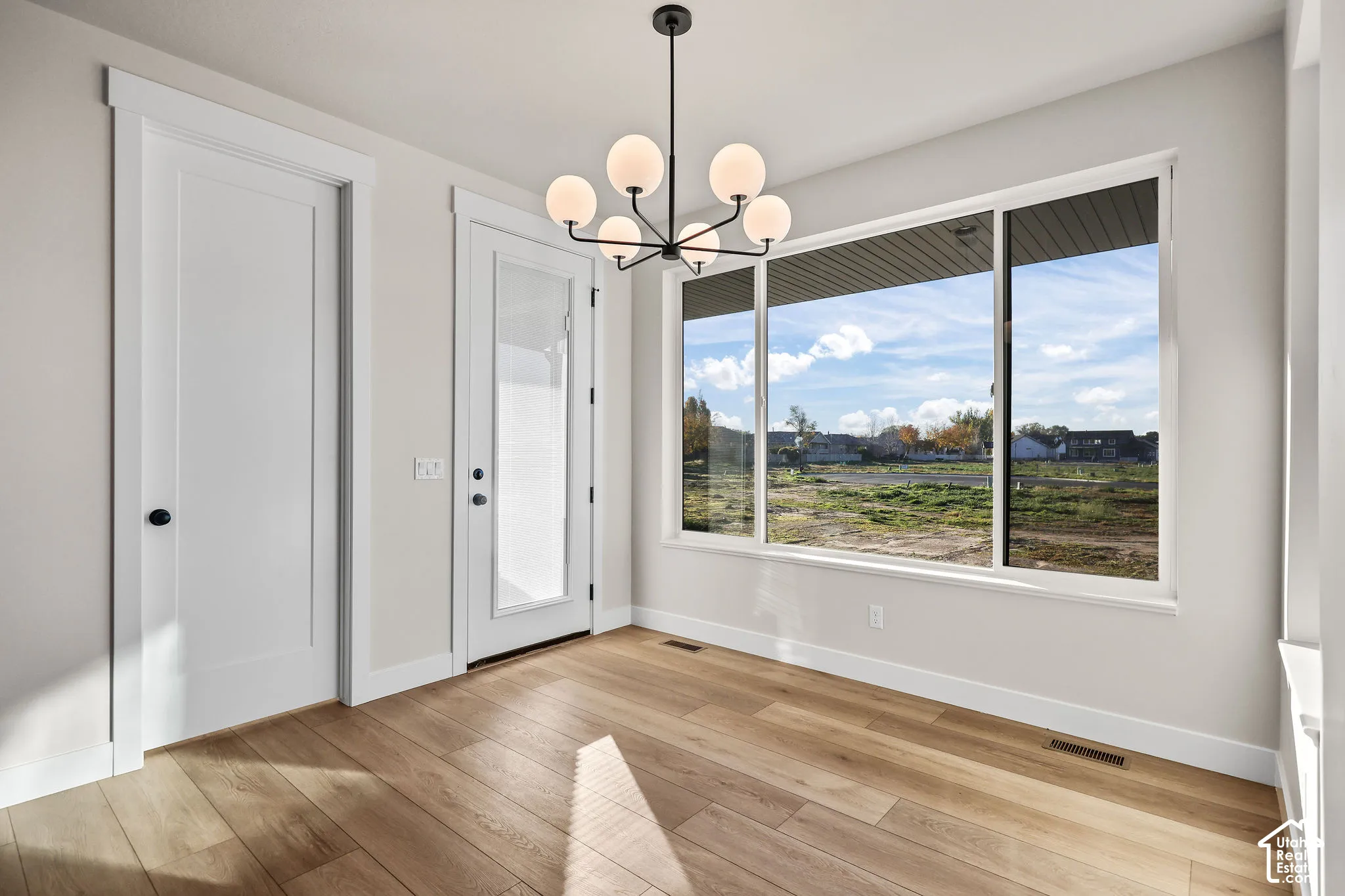 Bright interior space featuring a multi-pane window, wood-finish flooring, and a contemporary spherical chandelier