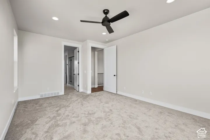 Spacious room featuring light-toned carpeting, recessed lighting, and a contemporary black ceiling fan