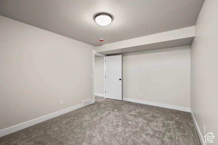 Carpeted room featuring a white interior door, recessed ceiling element, flush mount ceiling light, and baseboard trim