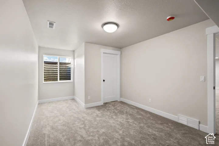 Spacious room featuring neutral carpeting, light wall paint, a double-paned window, and a white interior door with black hardware
