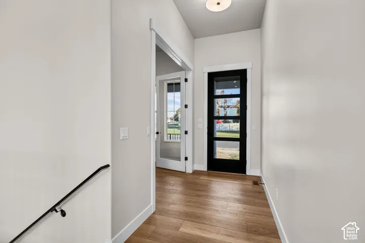 Foyer featuring wood-finish flooring, a modern black entry door with integrated glass panels, recessed ceiling light, and a white interior door