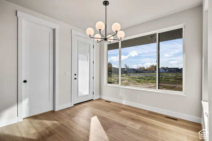 Bright interior space featuring a multi-pane window, wood-finish flooring, and a contemporary spherical chandelier
