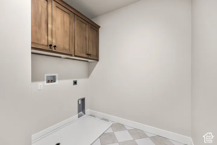 Laundry area featuring wood-finish cabinetry with matte black hardware, white walls, and a diamond-patterned tile floor