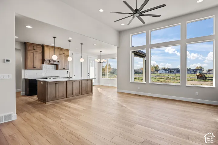 Spacious living area featuring large picture windows, light wood-finish flooring, and a modern ceiling fan