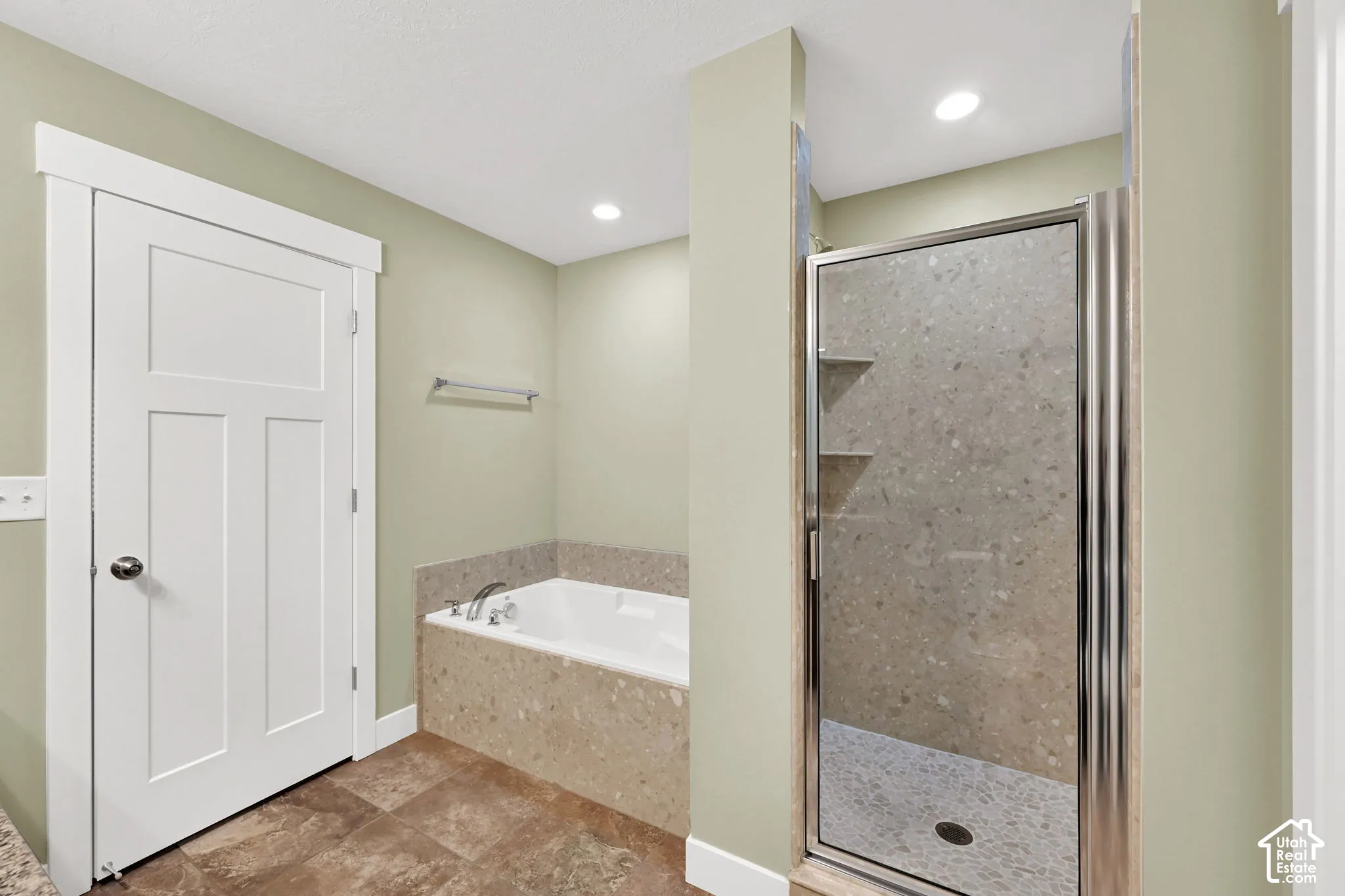 Soaking tub with stone-composite surround, walk-in shower with glass enclosure, integrated tile shelving, and tile flooring
