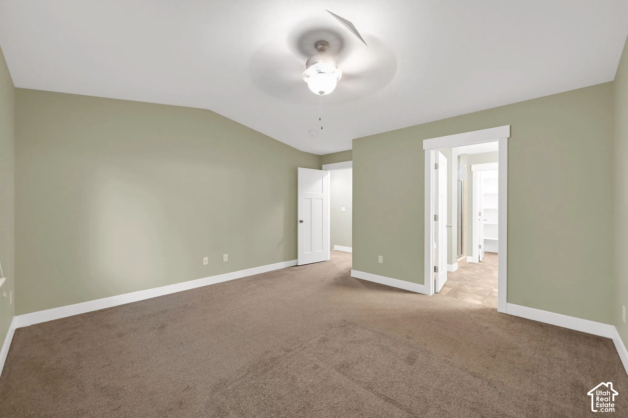 Vaulted ceiling featuring a central lighted ceiling fan, neutral wall tones, and carpeted flooring