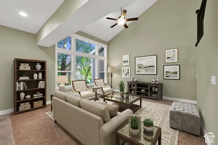 Vaulted ceiling featuring a central light fixture with a ceiling fan, expansive multi-pane windows, and neutral wall tones
