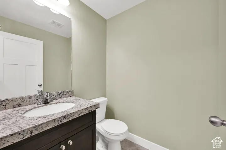 Dark-finish vanity cabinetry with stone-patterned countertop, integrated oval basin, polished chrome faucet, and large wall-mounted vanity mirror with multi-bulb fixture