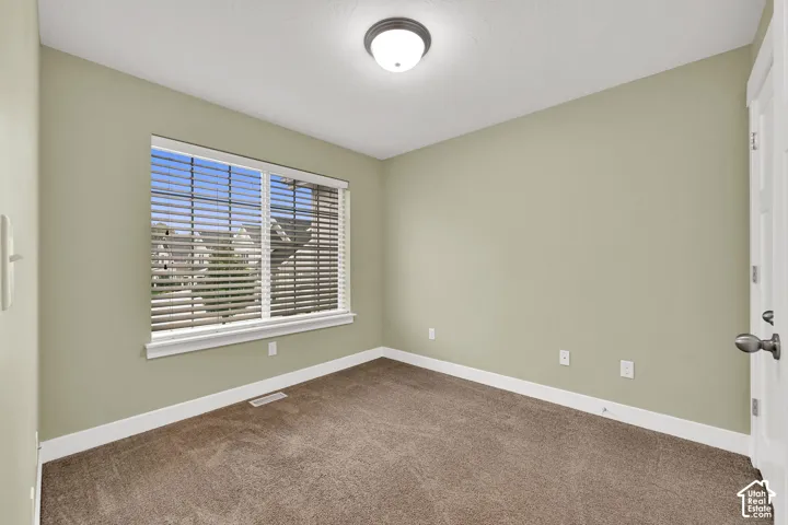 Neutral-toned room featuring carpeting, a single-pane window with horizontal blinds, and a flush-mount ceiling light fixture