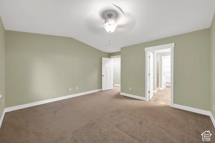 Vaulted ceiling featuring a central lighted ceiling fan, neutral wall tones, and carpeted flooring