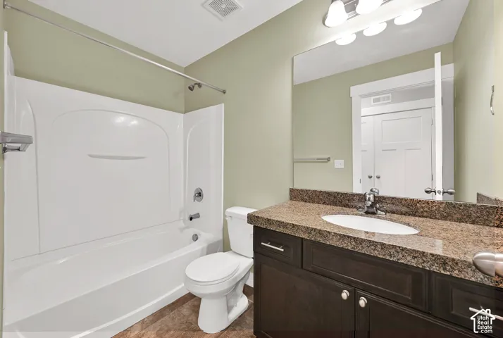 Full bathroom featuring a white tub-and-shower combination, dark wood-finish cabinetry, a stone-composite countertop with an integrated oval sink, and a large wall-mounted mirror
