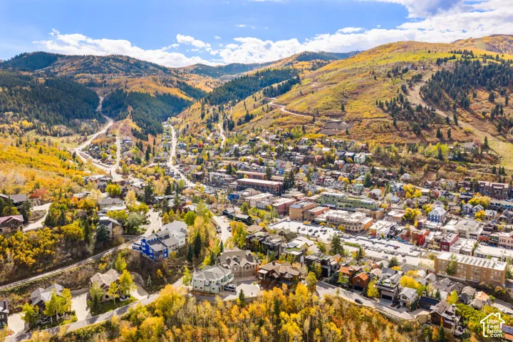 Aerial perspective of mountainous terrain featuring dense deciduous forest, winding infrastructure, and proximity to regional residential developments