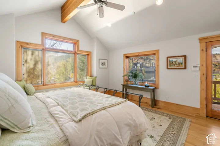 Vaulted ceiling featuring an exposed wood beam, natural wood trim, multi-pane windows, and a glass-paneled exterior door