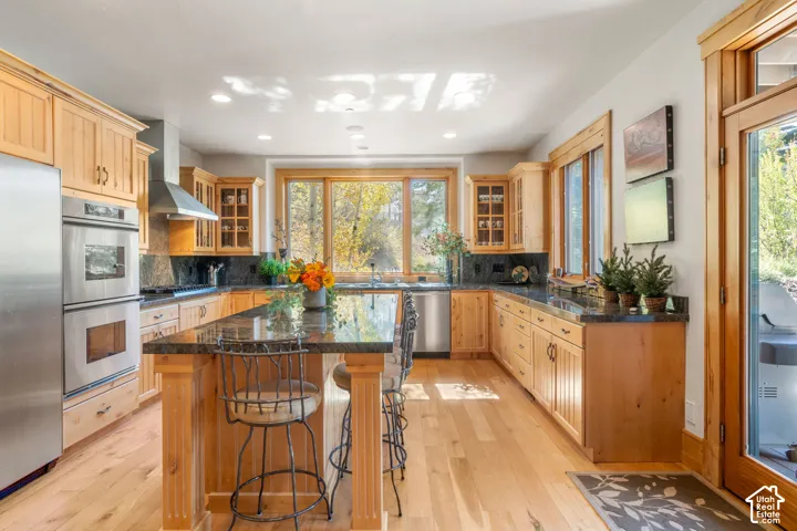 Kitchen featuring natural wood cabinetry, stone countertops, stainless steel double wall ovens, recessed lighting, and wood-finish flooring