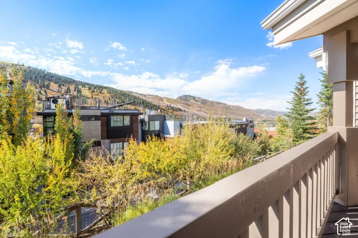 Outdoor balcony with vertical wood balusters, finished wood-surface flooring, and mountain backdrop