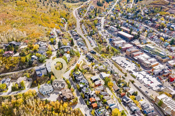 Aerial perspective of a multi-story residence featuring a multi-gabled roofline, stone and wood exterior siding, and a paved driveway, situated within a mountainous landscape