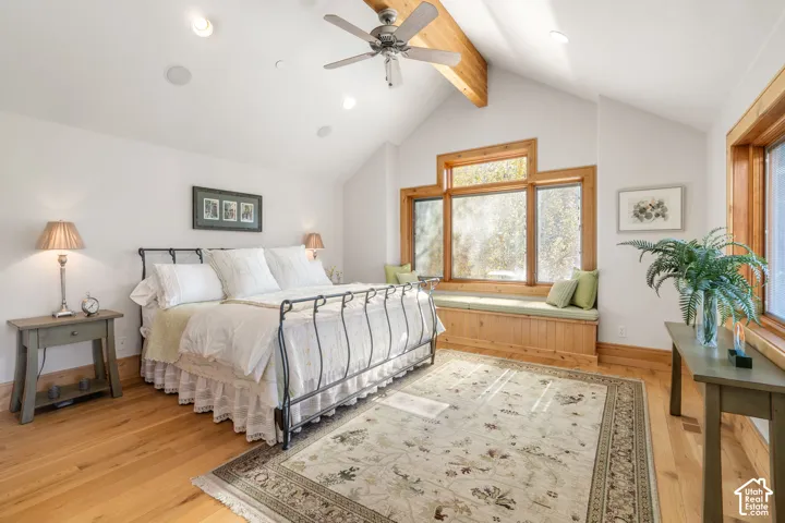 Vaulted ceiling with exposed wood beam, wood-finish flooring, and built-in window seat with wood trim