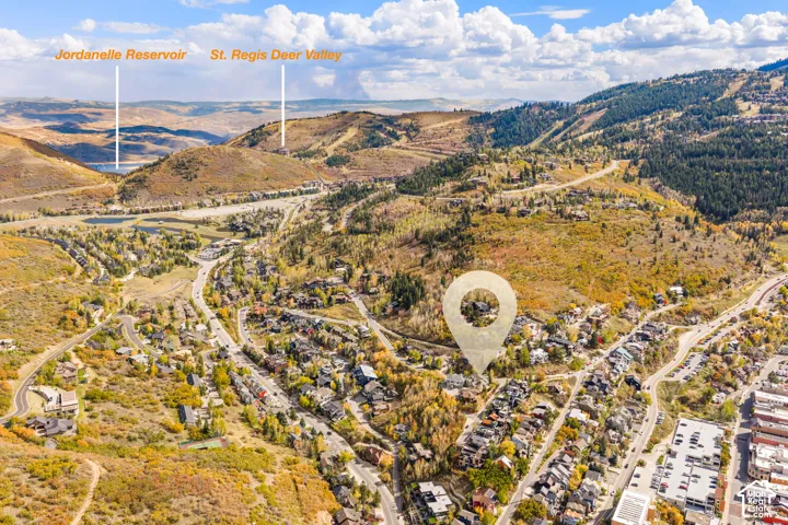 Aerial perspective of the hillside residential area featuring mountainous topography, dense clusters of mature trees, and proximity to Jordanelle Reservoir