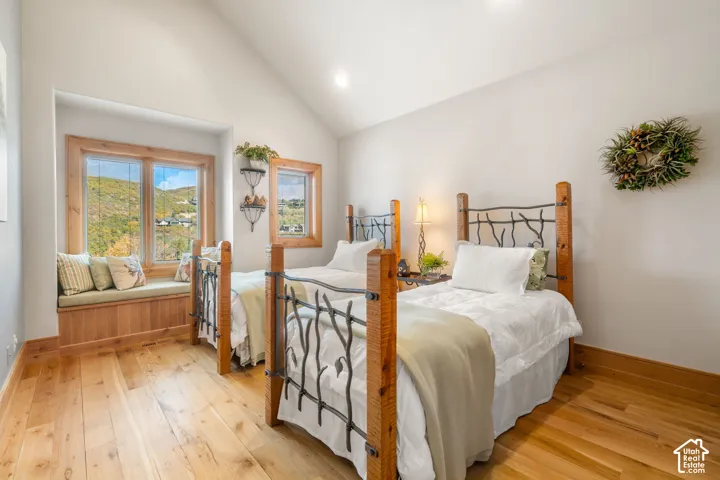 Vaulted ceilings, wood-finish flooring, built-in window seat, and wood-trimmed windows with natural scenery