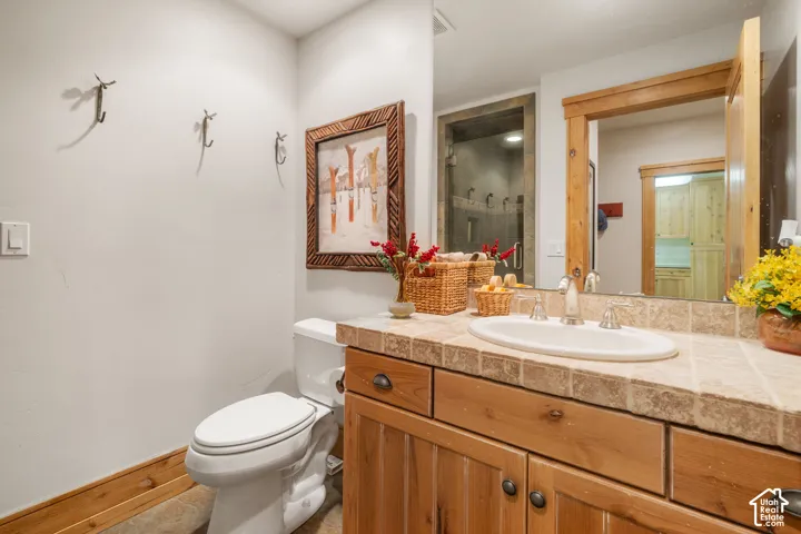 Bathroom featuring a custom wood vanity with a stone tile countertop, an undermount oval sink, and a large wood-framed mirror