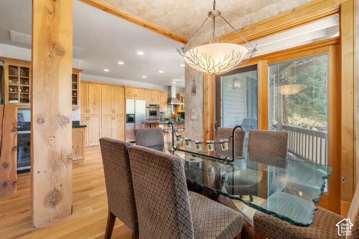 Natural wood cabinetry, wood-finish flooring, exposed structural timber post, recessed lighting, and a pendant fixture with a decorative metallic frame