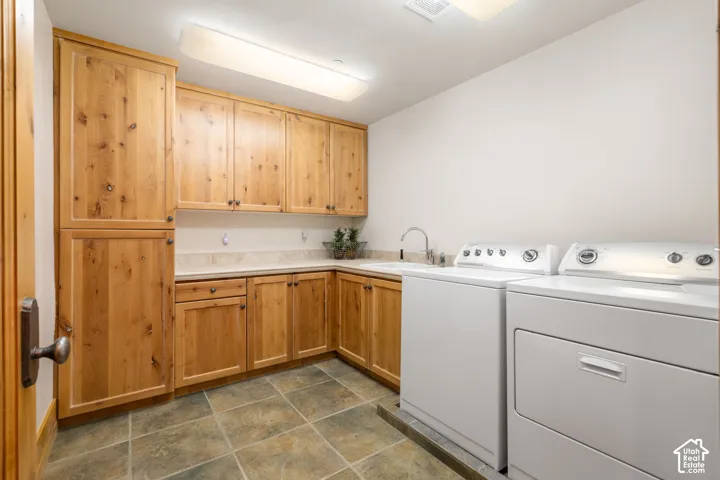 Natural wood-finish cabinetry, stone tile flooring, integrated countertop, built-in basin sink with chrome faucet, and overhead flush-mount lighting