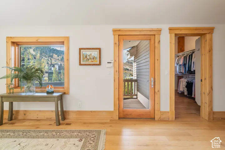 Natural wood-finish flooring, solid wood window and door casings, glass-panel exterior door, and built-in closet shelving
