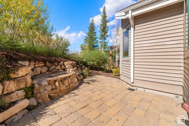 Exterior patio featuring stone paver flooring, a stacked stone retaining wall with an integrated stone bench, and horizontal lap siding