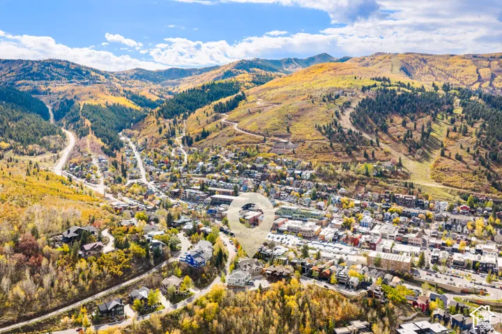 Aerial perspective featuring a multi-story residence situated among mountain topography and mature forest, with expansive natural scenery