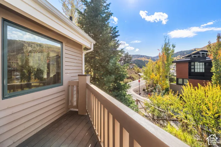 Exterior balcony featuring horizontal siding, wood-finish flooring, and a wooden railing, highlighting mountainous scenery and mature trees