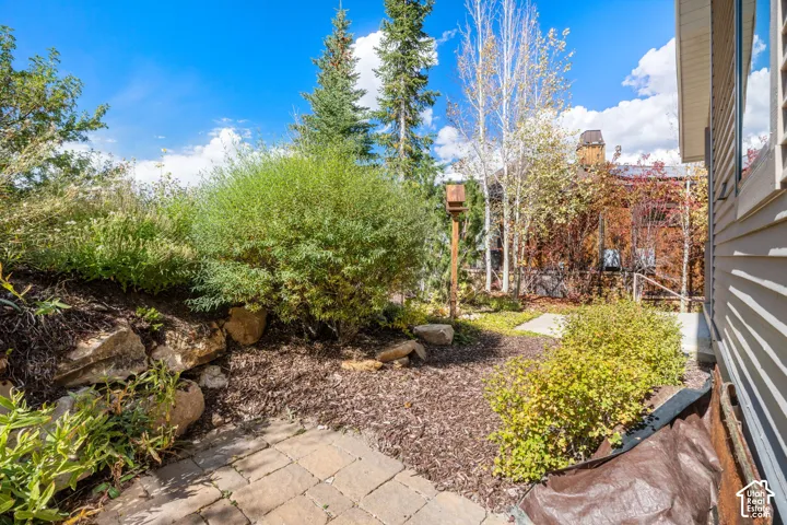 Exterior grounds featuring stone hardscaping, natural rock retaining elements, mature coniferous and deciduous trees, and wood-siding exterior wall finishes