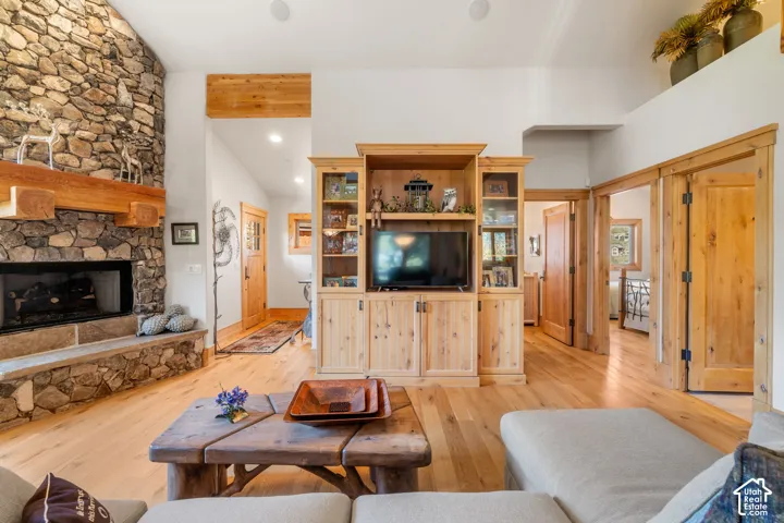 Floor-to-ceiling stone fireplace with a thick timber mantel, custom built-in wood cabinetry, wood-finish flooring, and natural wood trim throughout