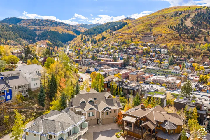 Aerial perspective of residential structures featuring multi-gable rooflines, stone masonry accents, shingled roofing, and private garage entries, set against a mountainous landscape