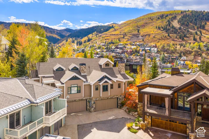 Multi-story mountain residence featuring stone veneer accents, shingled roofing, dual integrated garages, and dormer window detailing