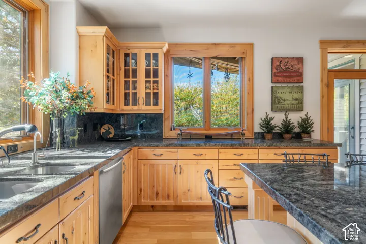 Kitchen featuring natural wood cabinetry, stone countertops, stainless steel undermount sink with a gooseneck faucet, wood-finish flooring, and natural wood window casing