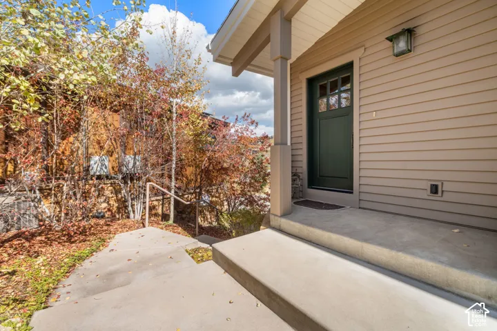 Covered entryway featuring horizontal lap siding, a dark-finished door with transom windows, a concrete porch, and a metal handrail