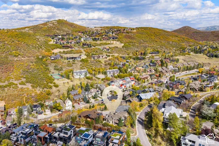Aerial perspective of a multi-level residence featuring stone and timber exterior cladding, a pitched roofline, and established coniferous and deciduous trees within a mountain landscape