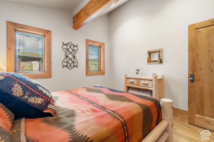 Exposed wooden ceiling beam, natural wood window trim, solid wood door, and wood-finish flooring