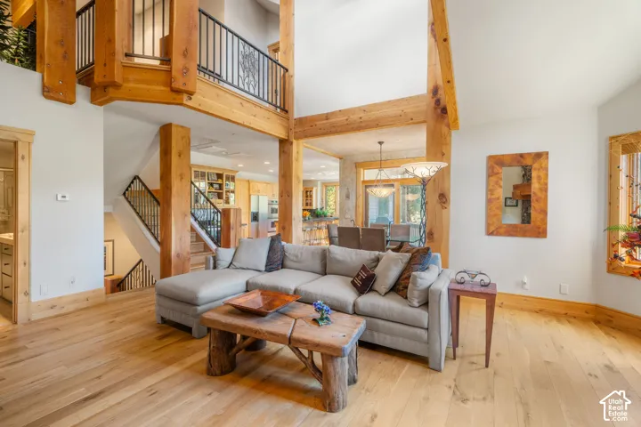 Great room featuring exposed timber framing, high ceilings, wood-finish flooring, and a metal staircase railing