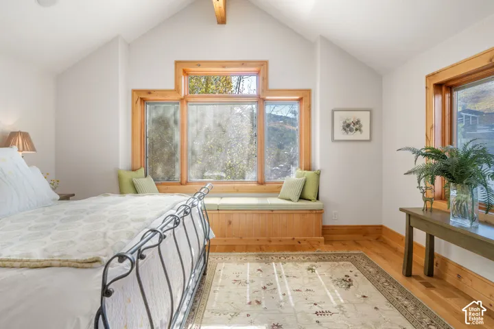 Vaulted ceiling with exposed wood beam, large multi-pane windows with natural wood trim, and custom built-in window seating