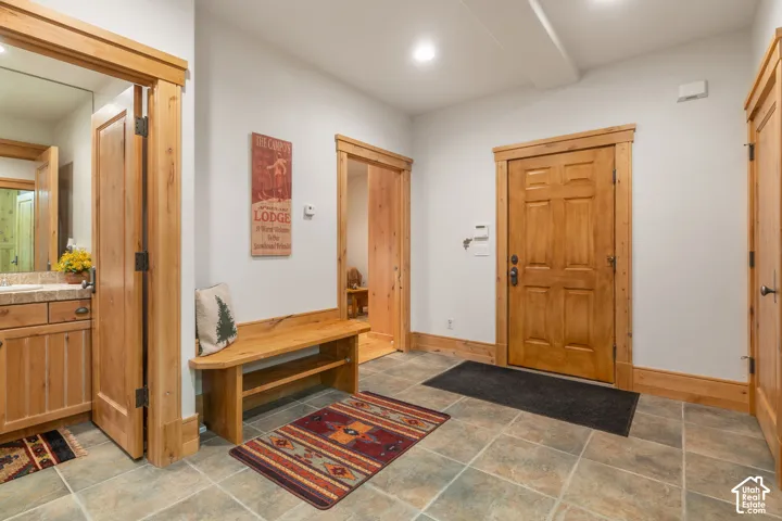 Entryway featuring natural wood trim, six-panel wood door, built-in wooden bench, tile flooring, and recessed lighting