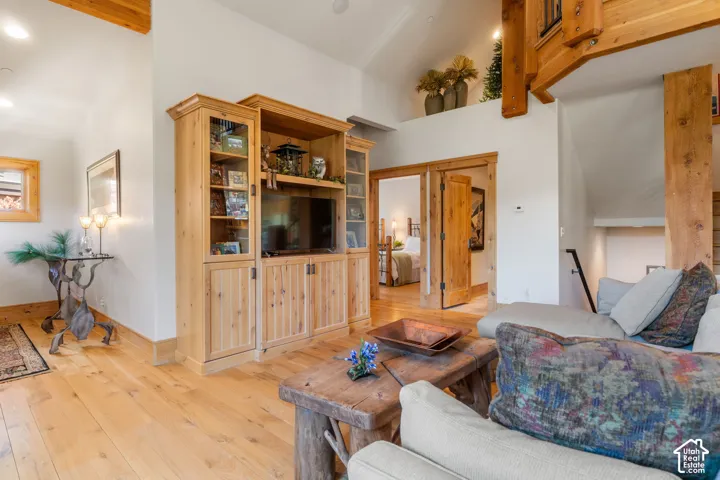 Vaulted ceiling featuring exposed timber beams, wood-finish flooring, and built-in natural wood cabinetry