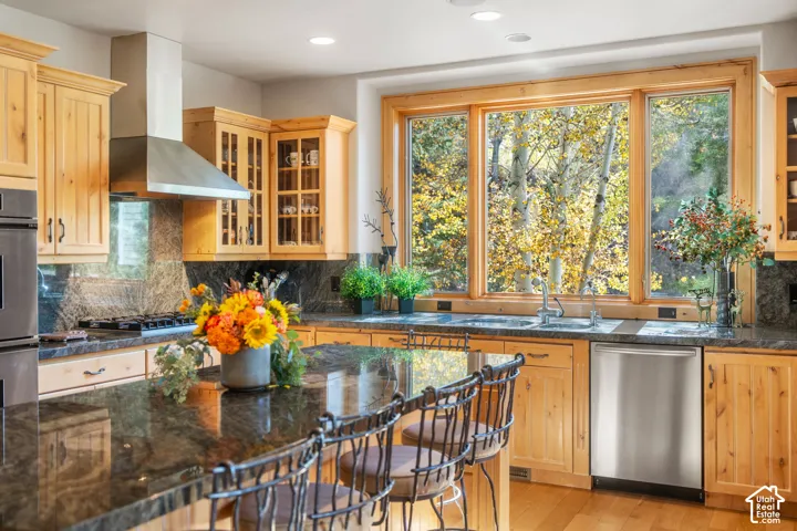 Kitchen featuring natural wood cabinetry, polished stone countertops, stainless steel appliances, a center island, and a large multi-pane picture window