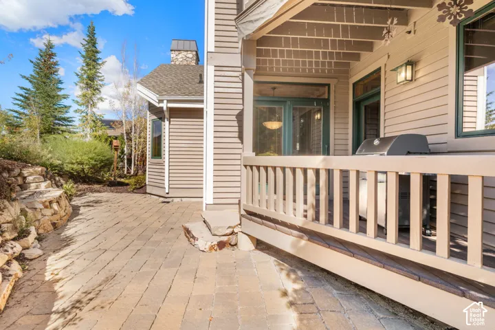 Stone-paved patio featuring a tiered rock retaining wall, siding exterior, and covered porch with wooden railings