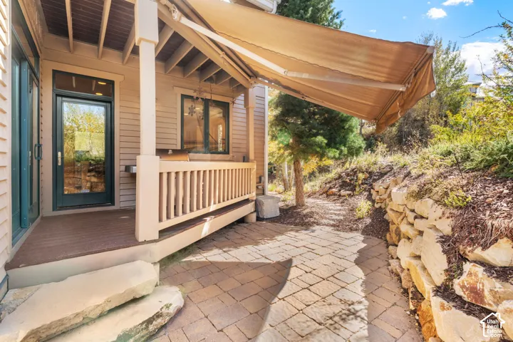 Covered deck with composite wood-finish decking, retractable awning, natural stone paver patio, and integrated retaining wall