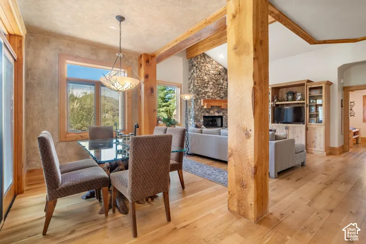 Wood-finish flooring, exposed timber support columns, stone fireplace hearth, textured wall finishes, and custom built-in cabinetry