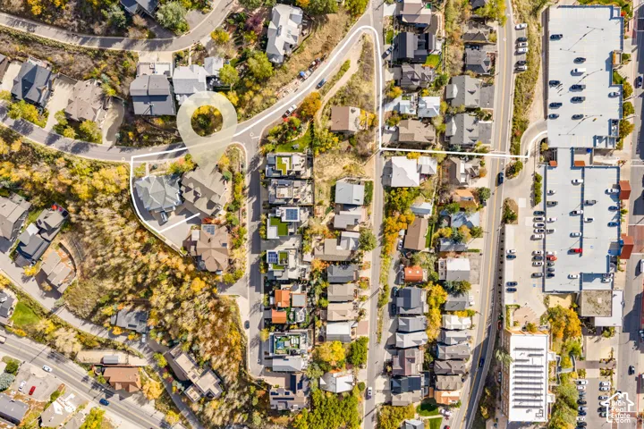 Aerial perspective of a multi-level residential structure featuring a multi-gabled roofline, concrete driveway, stone and composite siding, and established hillside landscaping