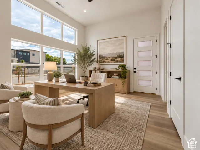 Casita/Office area featuring expansive floor-to-ceiling windows, wood-finish flooring, and a multi-panel frosted exterior glass door. Home is virtually staged